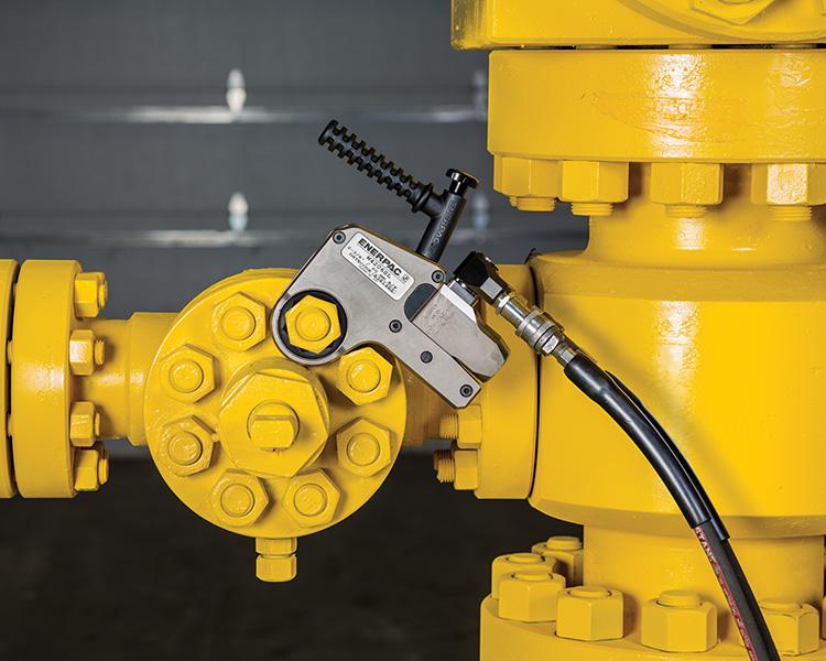 Un travailleur de la construction portant un casque, un gilet de sécurité et une ceinture à outils, se tient fièrement à côté d'un escabeau Featherlite jaune dans un environnement intérieur lumineux.