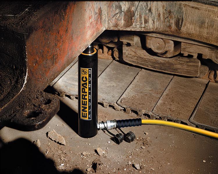 Un travailleur de la construction portant un casque de sécurité, un gilet de sécurité et une ceinture à outils se tient avec confiance à côté d'une échelle Featherlite jaune dans un environnement intérieur lumineux.