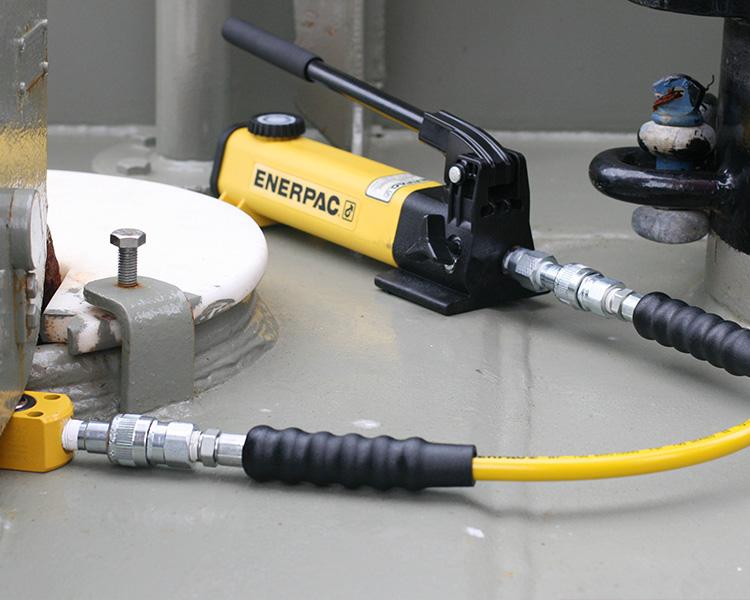 A small enerpac handpump that is connected to a small lifting cylinder.