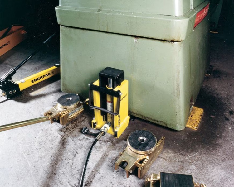 Un ouvrier de construction portant un casque de sécurité, un gilet de sécurité et une ceinture à outils se tient à côté d'une échelle Featherlite jaune dans un cadre intérieur lumineux.