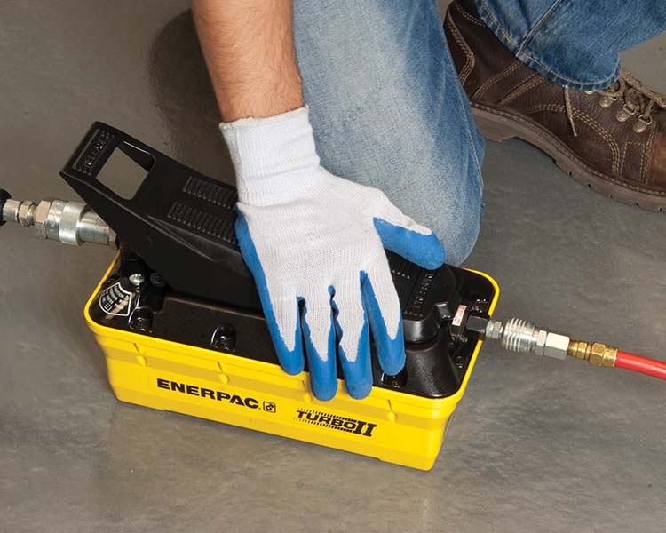 Un ouvrier de construction portant un casque de sécurité, un gilet réfléchissant et une ceinture à outils se tient avec confiance à côté d'une échelle Featherlite jaune dans un environnement intérieur lumineux.
