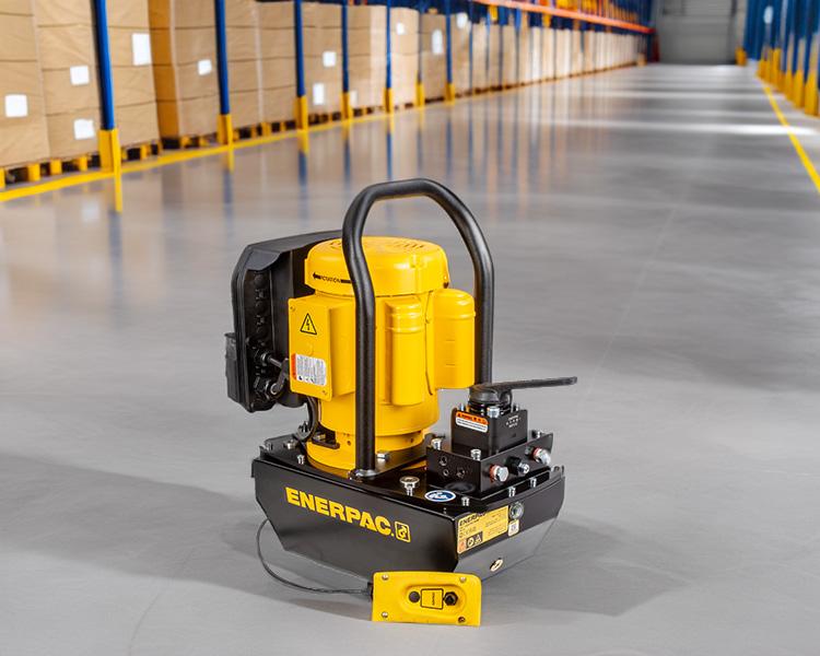 Un ouvrier de construction portant un casque de sécurité, un gilet réfléchissant et une ceinture à outils se tient avec confiance à côté d'une échelle Featherlite jaune dans un environnement intérieur lumineux.